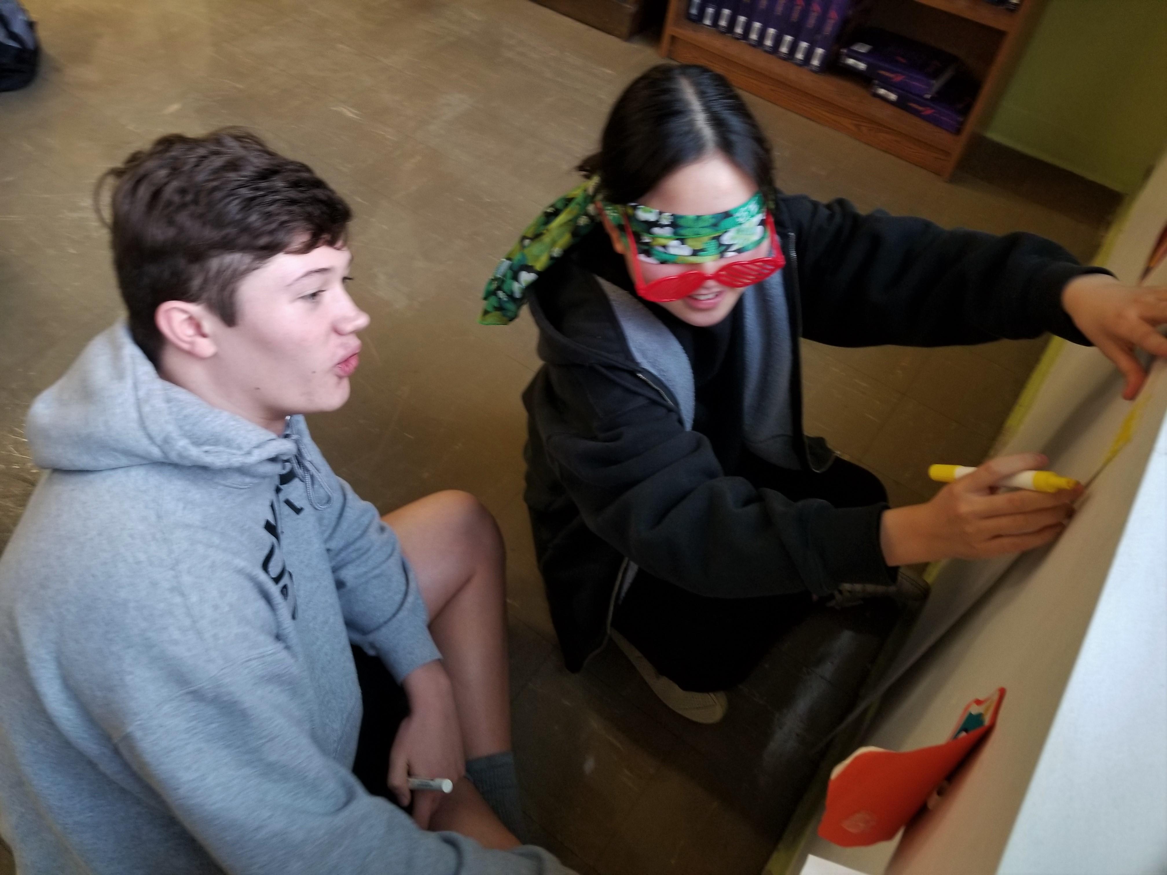 Blindfolded student receiving directions from a classmate.